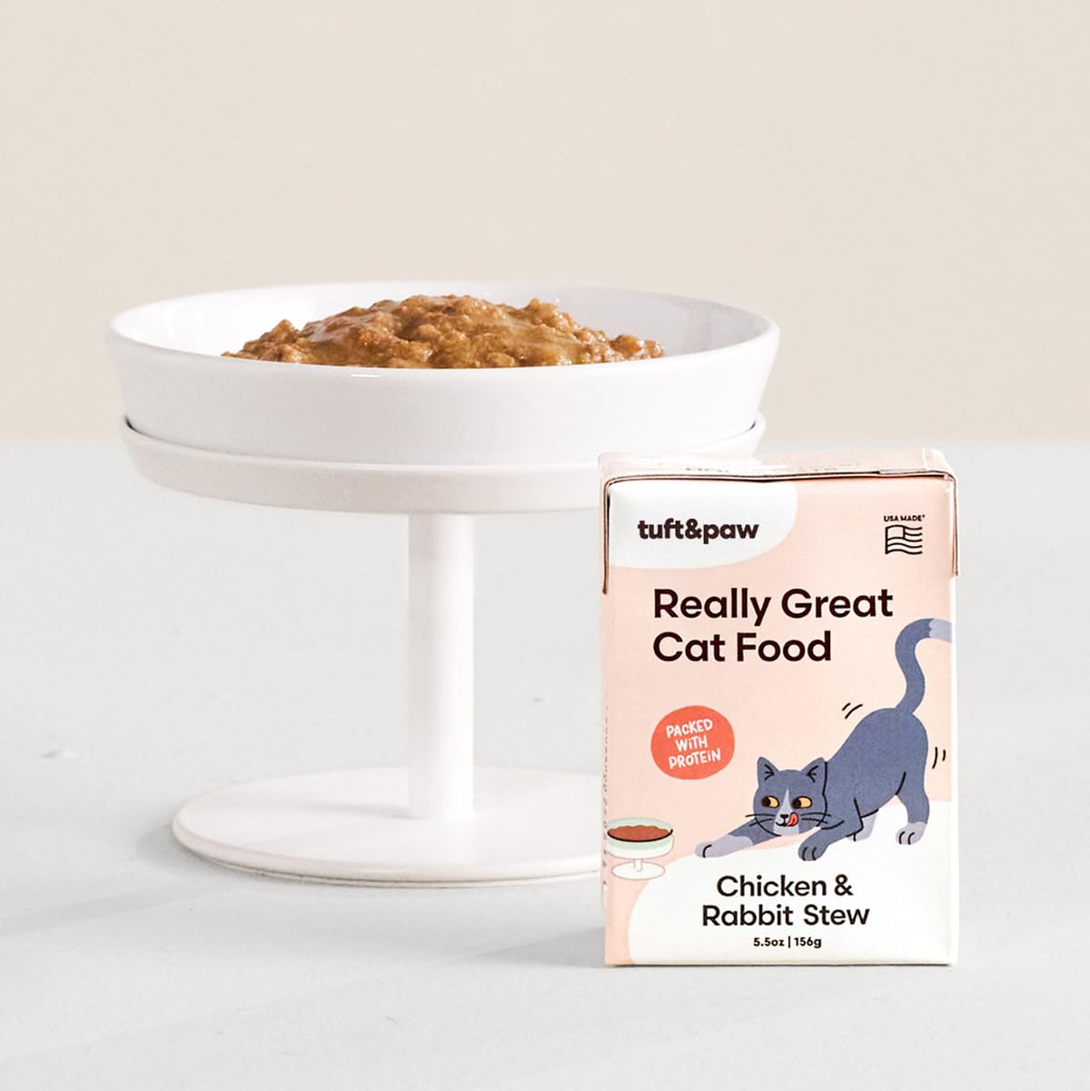 TUFT + PAW wet cat food closeup shows chunky chicken-rabbit stew morsels for palatability.